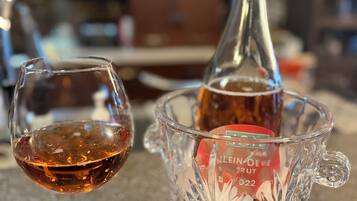 A glass of red wine and a bottle in a glass decanter on a countertop.
