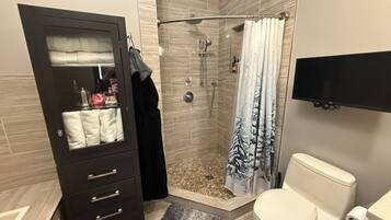 A bathroom with a shower, toilet, and a vanity with a mirror and towel rack.
