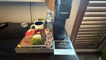 A breakfast tray with coffee maker, water bottle, mugs, and food items.