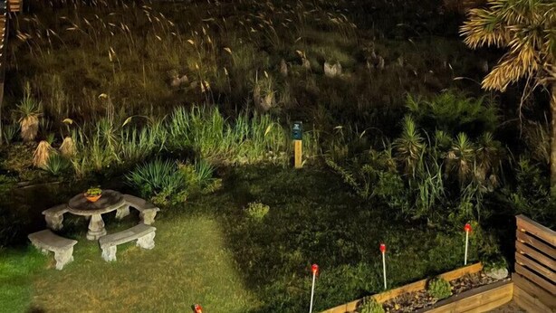 A nighttime view of a coastal area with a stone wall, grassy terrain, and a small table with benches. - #5 Steps away from beach! 1 mile from CB Boardwalk (Carolina Beach)