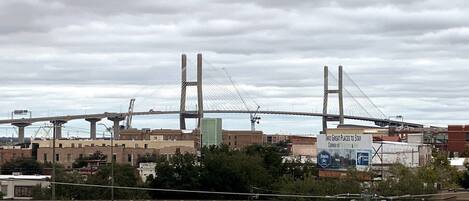 Un puente colgante grande con dos torres, rodeado de edificios industriales y un cielo nublado.