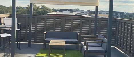 A rooftop patio with a pergola, seating area, and a small table.
