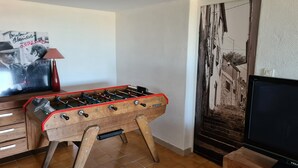Et værelse med et træfodboldbord, et fjernsyn, et plakat og et flisegulv.