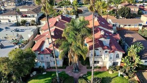 A large, multi-story house with a red-tiled roof, surrounded by palm trees and a well-maintained lawn. - 1 Block to Pacific Beach/FOOD/Bars, Updated, 2-Car Garage w/fee, Yard, Sleeps 8! (San Diego)