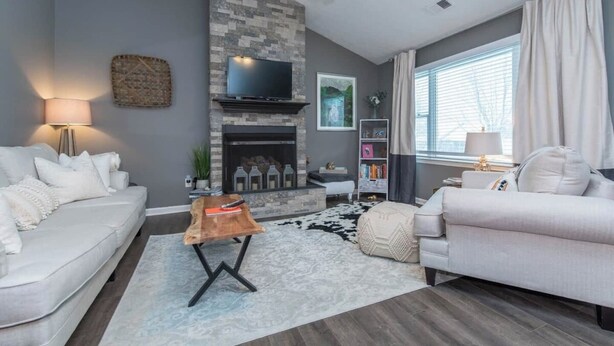 Un salon moderne avec une cheminée, des canapés blancs, une table basse et un ventilateur de plafond.