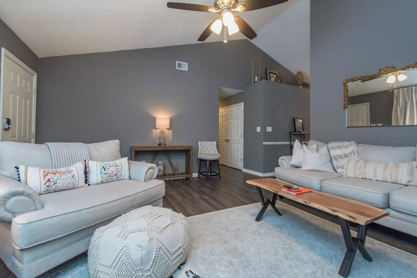 A living room with two light grey sofas, a wooden coffee table, and a ceiling fan.