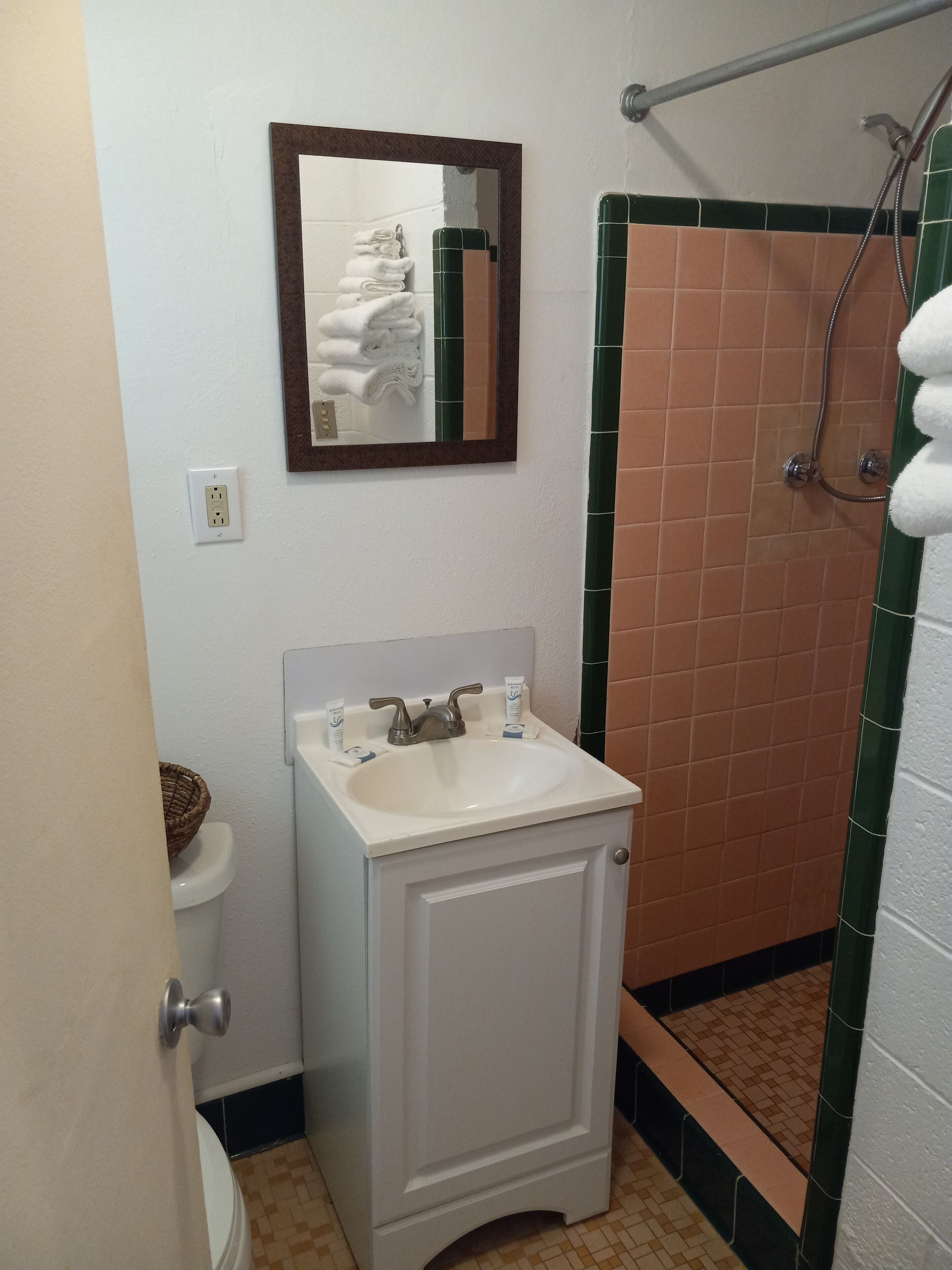 Une salle de bain avec un lavabo blanc, un miroir, un porte-serviettes et un espace douche.