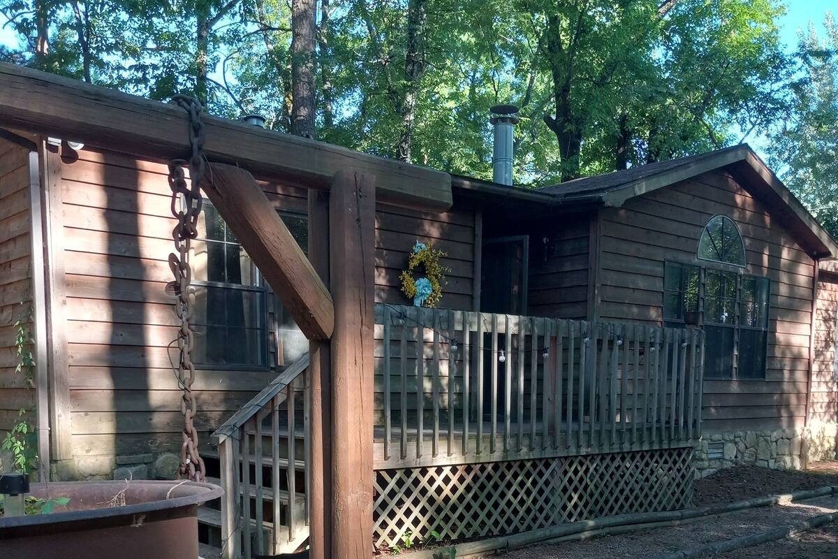 A wooden deck with a lattice railing, a hanging planter, and a house with a porch in the background.
