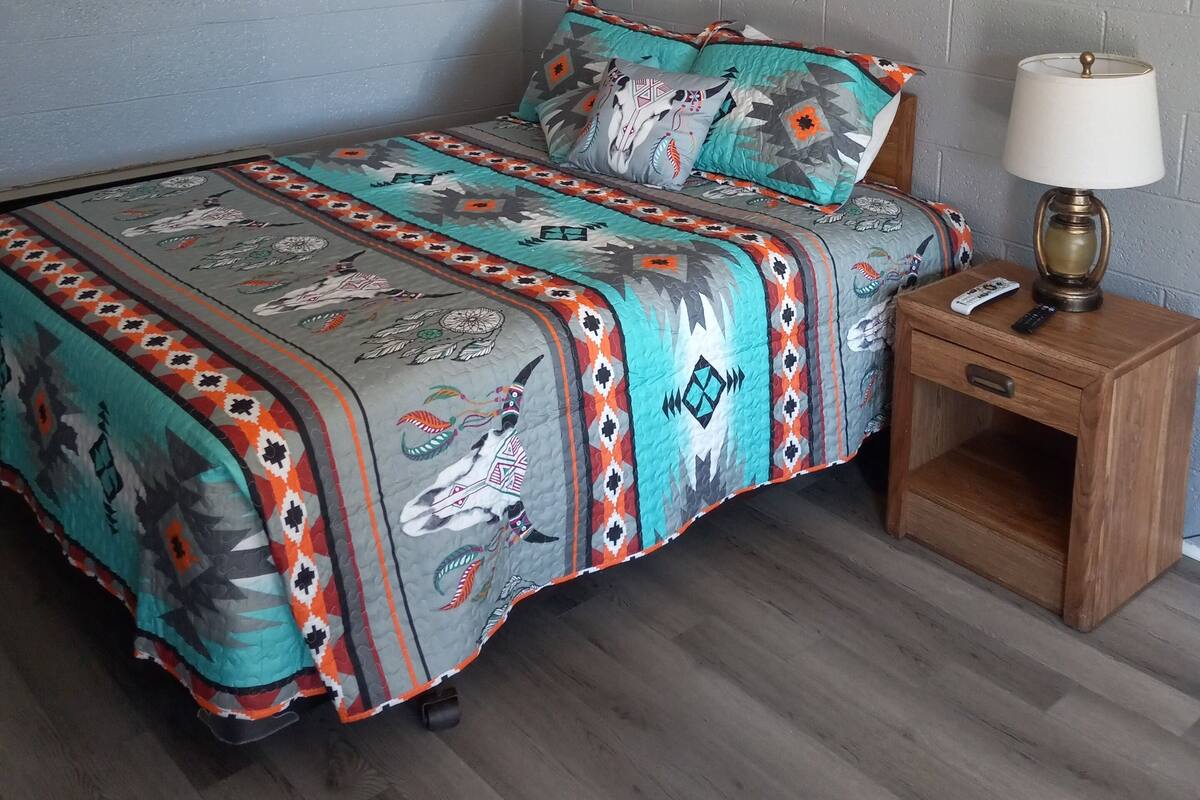 A bedroom with a bed, a nightstand, a lamp, and a ceiling fan.