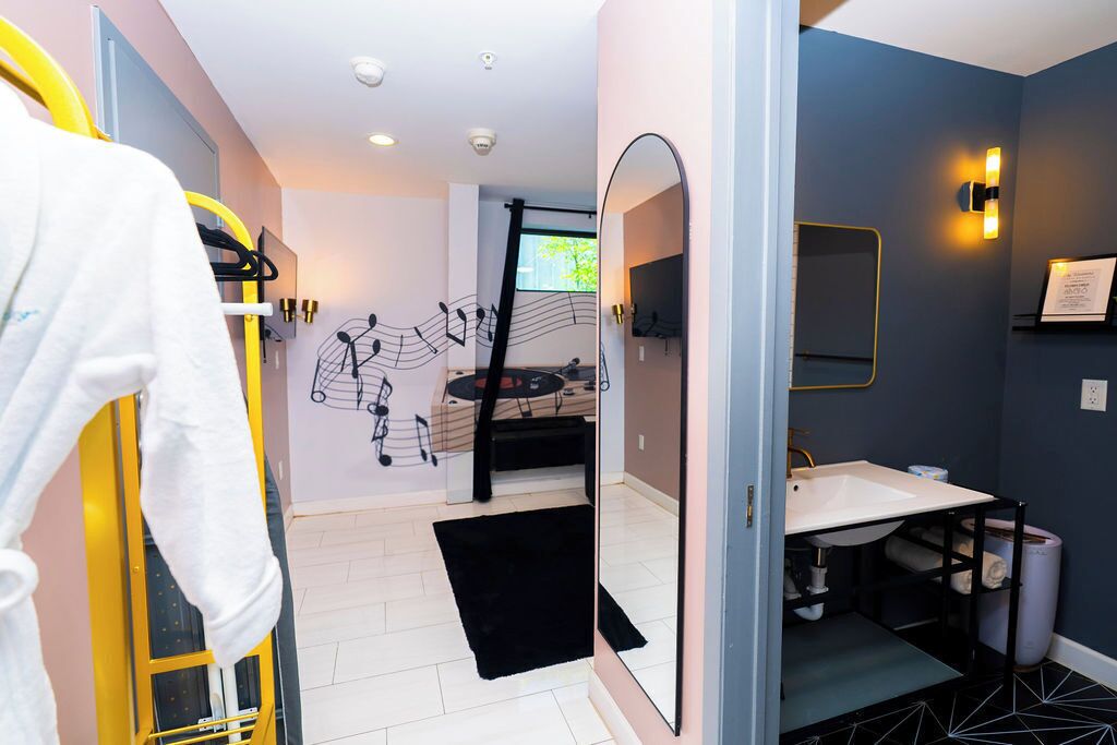 A modern bathroom with a mirror, sink, and a black rug.