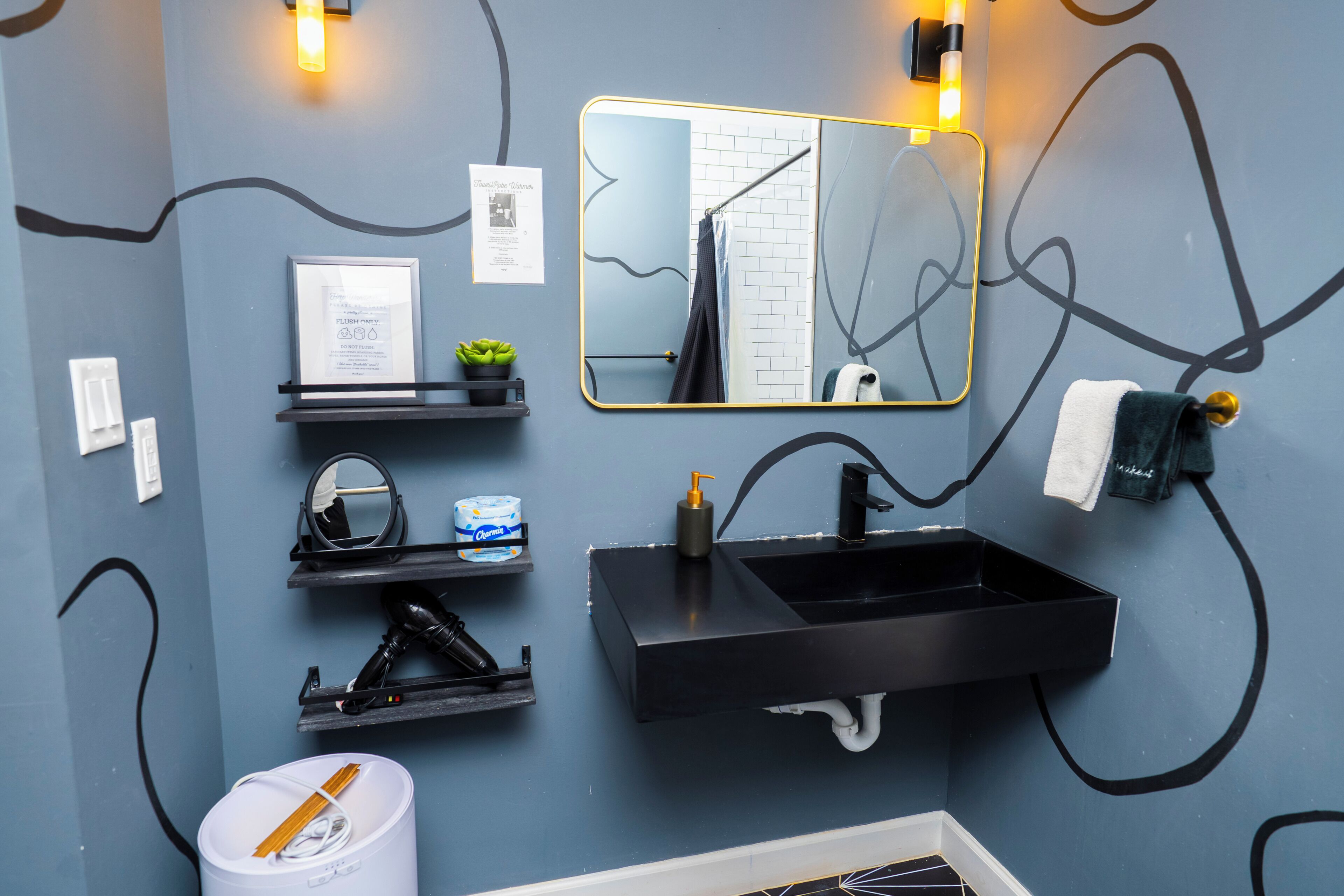 Een moderne badkamer met een zwart wastafel, een spiegel en een handdoekhouder.