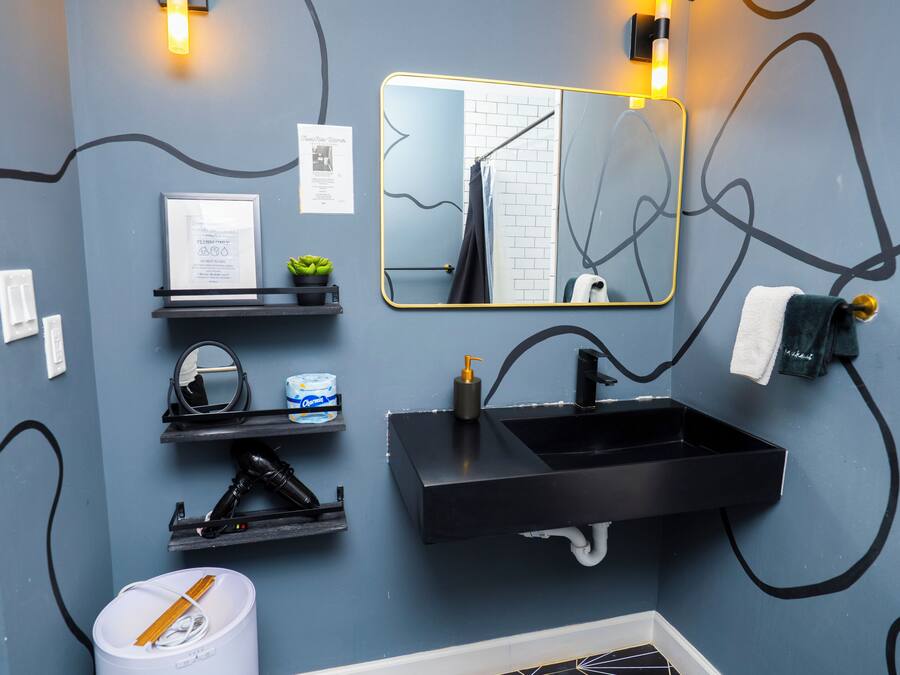 Een moderne badkamer met een zwart wastafel, een spiegel en een handdoekhouder.