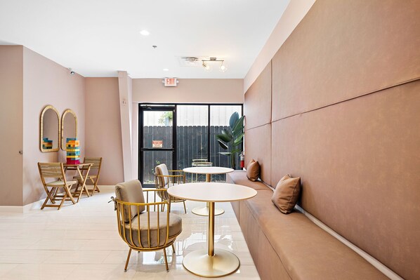 Un intérieur moderne avec un espace salon, des tables et une vue à travers une porte vitrée.