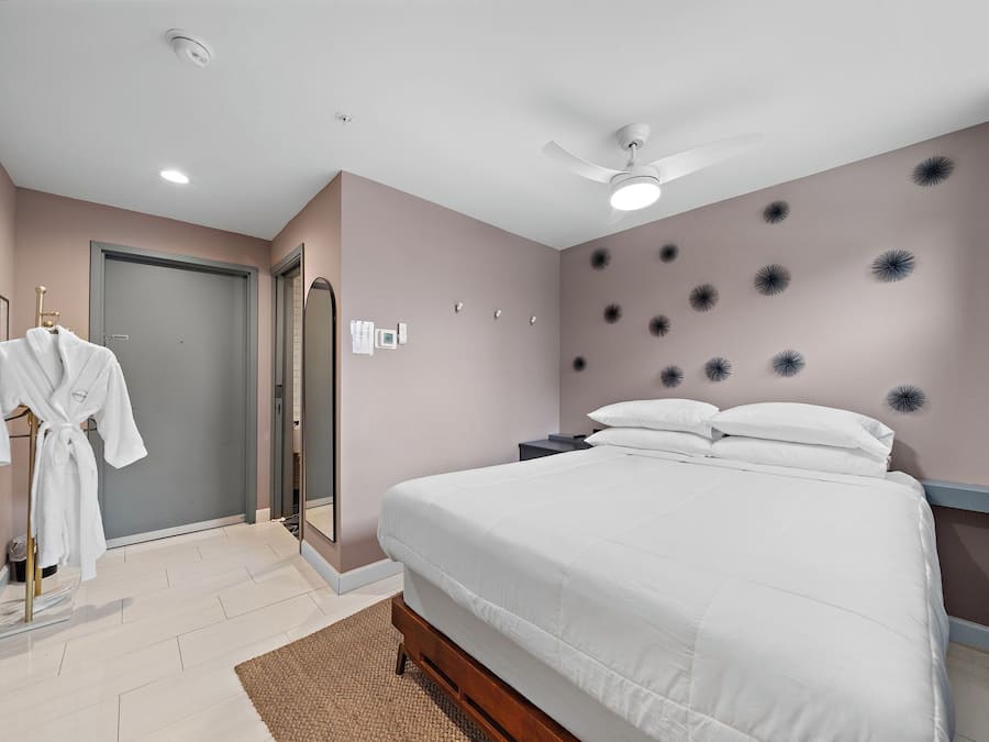 Un dormitorio con cama, perchero, ventilador de techo y una pared decorada.