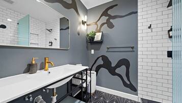 A modern bathroom with a white sink, gold faucet, and a black and white geometric floor.