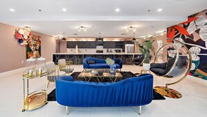 Uma sala de estar moderna com um sofá azul, uma mesa de centro de vidro e uma cadeira suspensa.