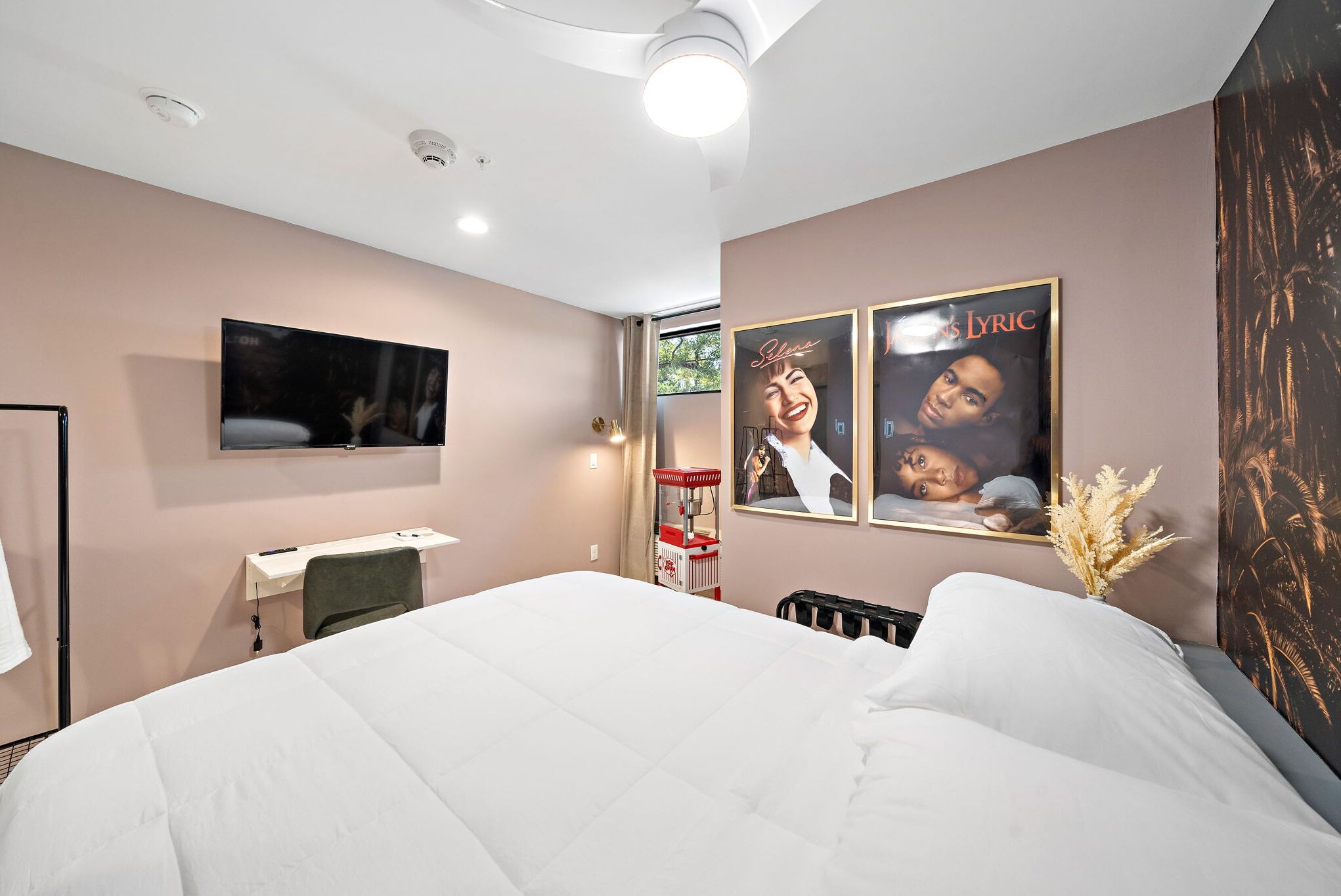 Una habitación de hotel moderna con una cama grande, un escritorio, un televisor de pantalla plana montado en la pared y dos carteles enmarcados en la pared.