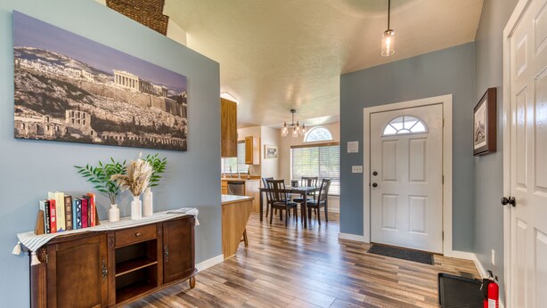A hallway with a wooden floor, a dining area with a table and chairs, a white door, and a fire extinguisher. - Modern 3BR w/ Mountain Views • Sleeps 8 • 2 car garage plus extra parking (Hamilton)
