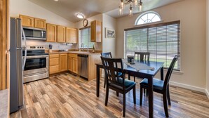 A modern kitchen with wooden cabinets, stainless steel appliances, and a dining area with a table and chairs. - Modern 3BR w/ Mountain Views • Sleeps 8 • 2 car garage plus extra parking (Hamilton)