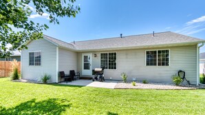 A single-story house with a covered patio, a grill, and a small garden area. - Modern 3BR w/ Mountain Views • Sleeps 8 • 2 car garage plus extra parking (Hamilton)