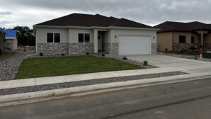 Ein Bungalow mit Garage, Steinuntergrund und gepflegtem Rasen.
