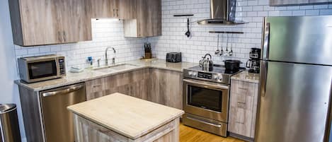 Una cocina moderna con armarios de madera, un refrigerador de acero inoxidable y un horno empotrado.