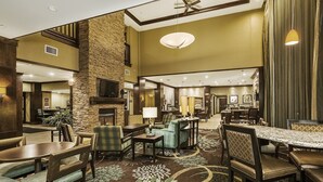 A spacious lobby with a high ceiling, a stone accent wall, a fireplace, and a variety of seating arrangements including sofas and chairs.