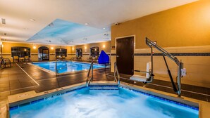 An indoor swimming pool with multiple lanes, a blue water feature, and a seating area with chairs.