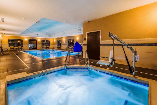 An indoor swimming pool with multiple lanes, a blue water feature, and a seating area with chairs.