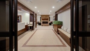 A hotel lobby with a central fireplace, seating areas, and a reception desk.