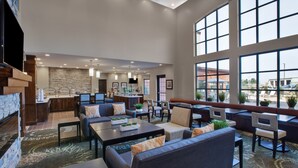 A spacious lobby with a stone fireplace, comfortable seating areas, and large windows offering views of the outside.