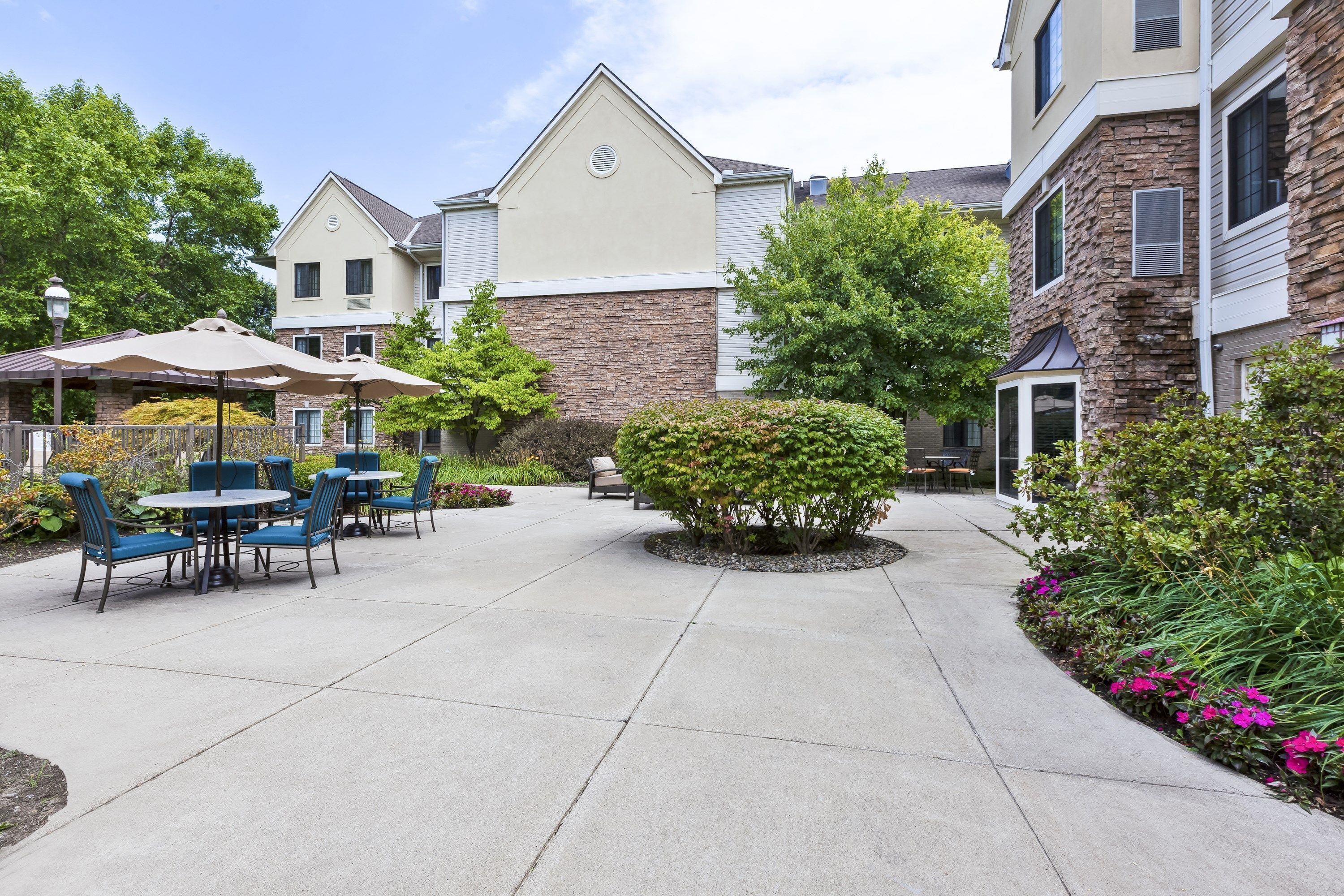Paved walkway along the building exterior with mature trees lining the path