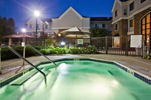 Piscina com escada de metal, cercada por uma grade, e um edifício com aviso de que não é permitido comer fora.