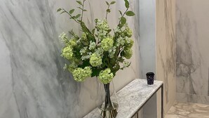 Un banc de marbre amb un ram de flors davant d'una paret de marbre.