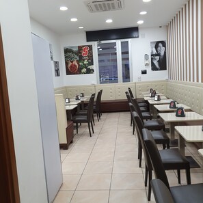 A restaurant with booths and tables, a tiled floor, and wall decorations including a coffee bean image and a poster.