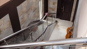 A staircase with glass railings and a stone wall. - Luxurious Two Bedroom Double Storey Apartments (Lusaka)