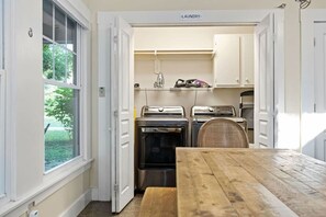 A laundry room with a wooden table, two washing machines, and a dryer. - 3 Houses 30 guests Country 14 acre Pecan Orchard (Maxwell)