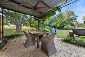 An outdoor patio with wicker furniture, a ceiling fan, and a view of a fenced garden. - 3 Houses 30 guests Country 14 acre Pecan Orchard (Maxwell)