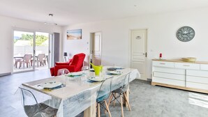 A spacious dining area with a large table, chairs, and a view of the outdoors. - Le Gois - Jardin -  Marais salants (Beauvoir-sur-Mer)