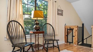 A room with two wooden chairs, a table with a lamp, a window with curtains, and a staircase. - Bird House Countryside Pecan Farm 6acre San Marcos (Maxwell)