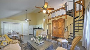 A spacious living room with a high ceiling, a dining area, and a kitchen. There is a staircase leading to an upper level. - Bird House Countryside Pecan Farm 6acre San Marcos (Maxwell)