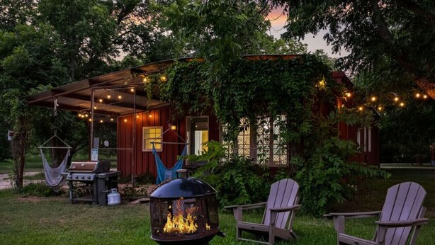 A covered outdoor seating area with a grill, chairs, and a fire pit. - RoosterHouse Countryside Pecan Farm 6ac SanMarcos (Maxwell)