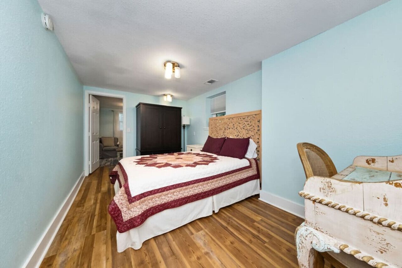 Un dormitorio con una cama grande, piso de madera y pared de color azul claro.