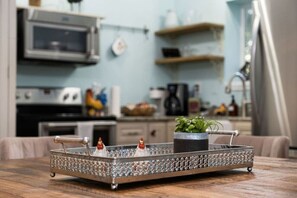 A kitchen with a microwave, stove, and various kitchen items on shelves.