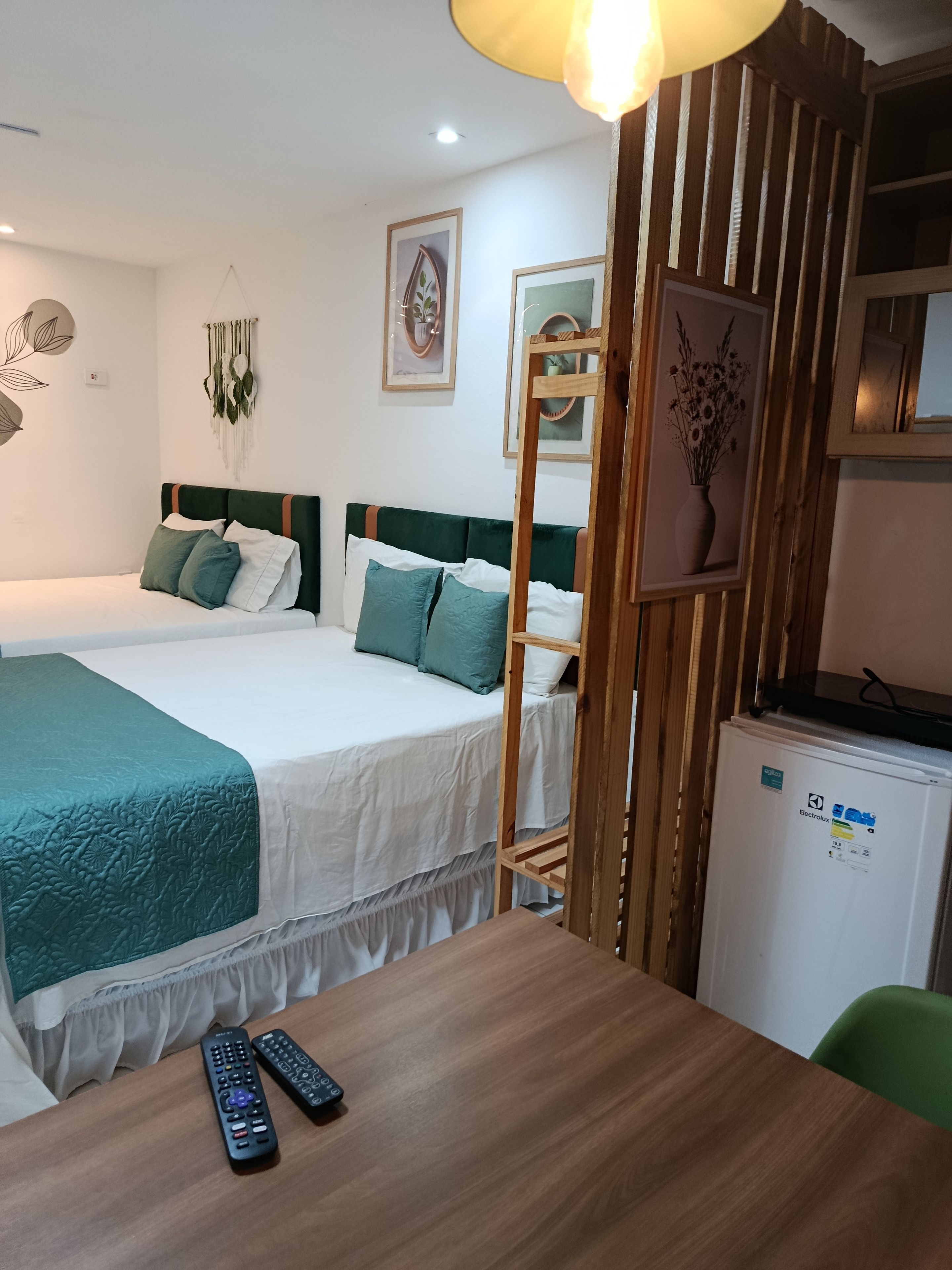 A hotel room with a bed, bedside table, and a small refrigerator.