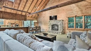 Ein Blockhaus-Interieur mit Kamin aus Stein, Holzbalkendecke und einer gemütlichen Sitzecke.