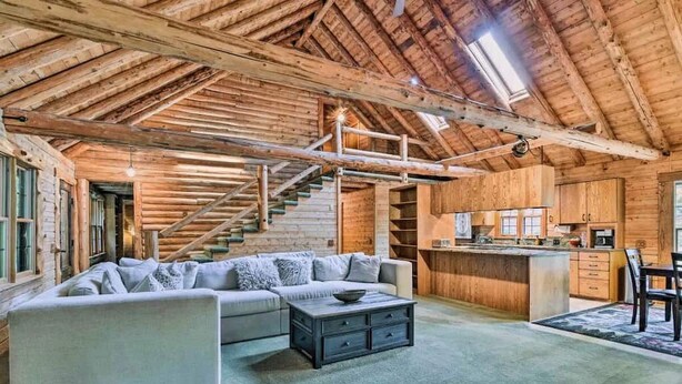 Ein rustikaler Innenraum einer Blockhütte mit Wohnbereich, Küche und Treppe.