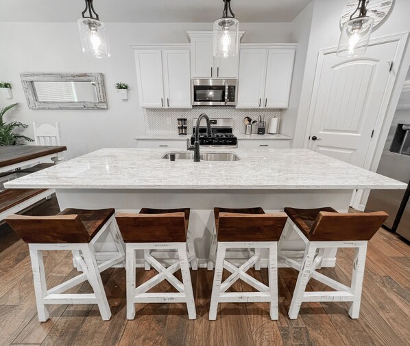 Enjoy cooking in this well-equipped kitchen with a central island, sink, microwave, and stove.