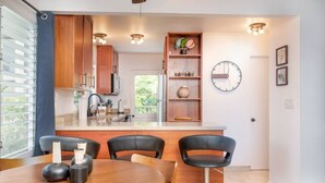 A modern kitchen with wooden cabinets, a built-in island, and pendant lighting.