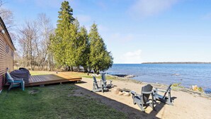 Une terrasse au bord du lac, avec des fauteuils Adirondack, une plateforme en bois et une vue sur le lac.